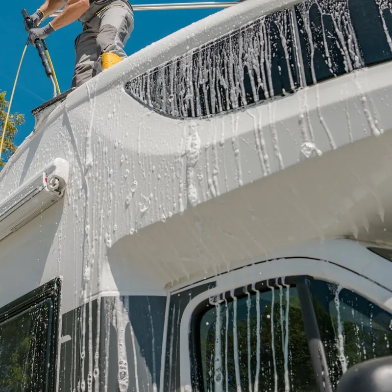 Technician washing the roof line of a motorhome during mobile RV detailing in Oakland